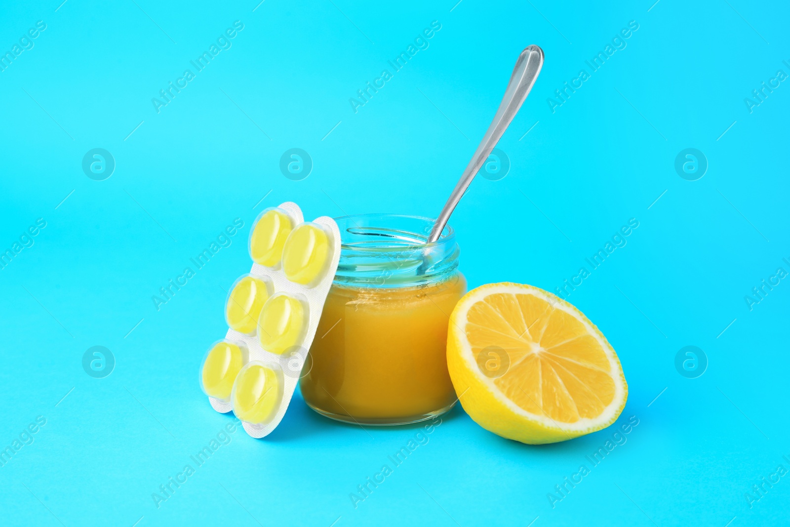 Photo of Blister with cough drops, fresh lemon and honey on light blue background