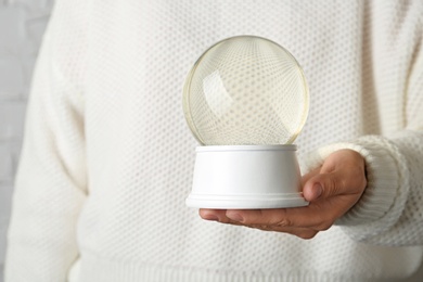 Photo of Woman wearing white sweater holding empty snow globe, closeup