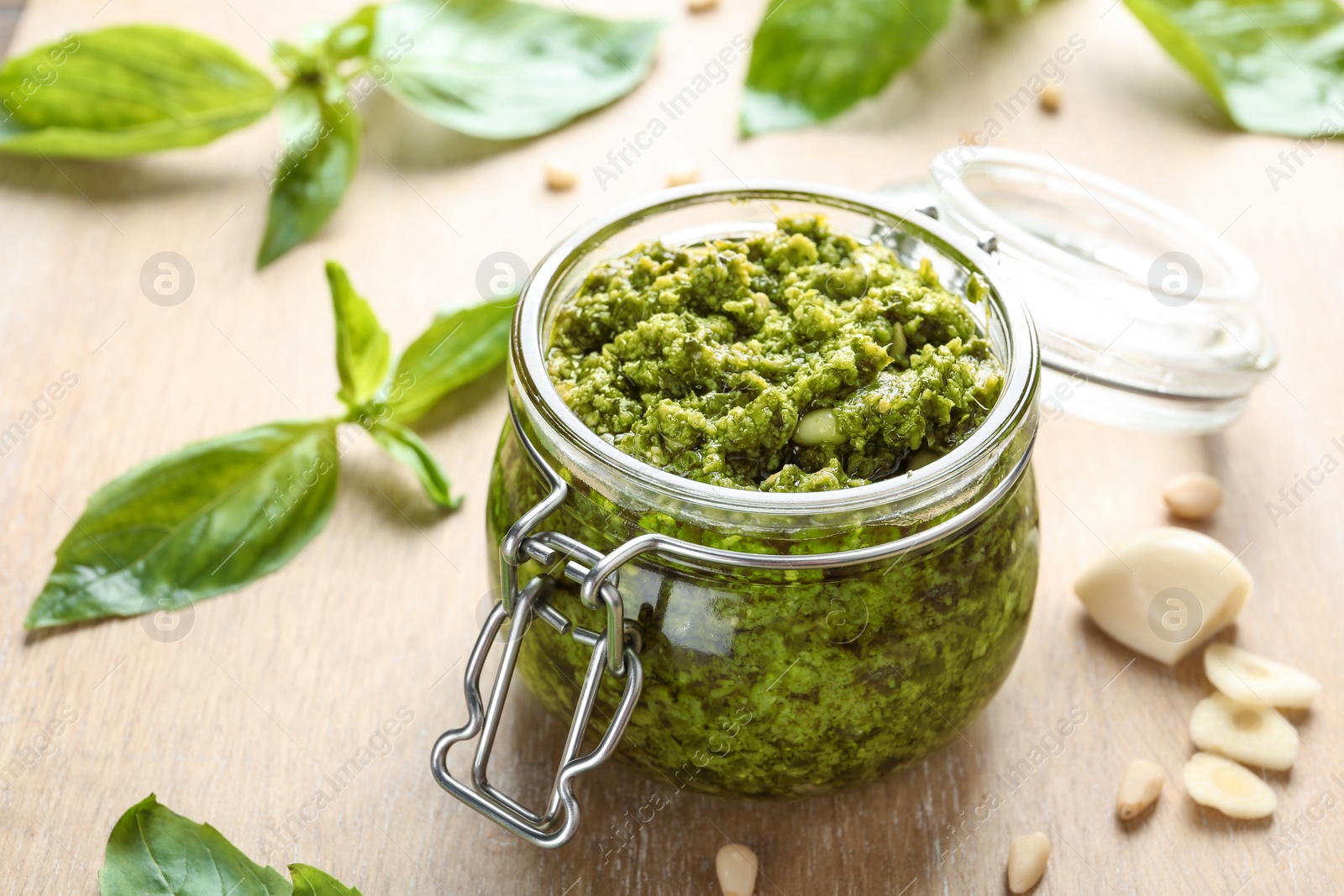 Photo of Jar of tasty pesto sauce on table, closeup