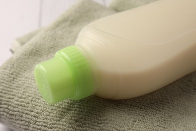 Photo of Bottle of fabric softener on terry towel, closeup