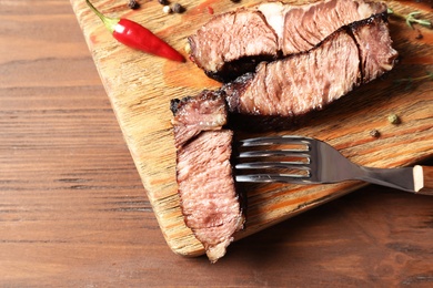 Photo of Flat lay composition with delicious barbecued meat on wooden background. Space for text