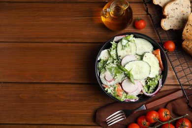 Photo of Bowl of delicious vegetable salad dressed with mayonnaise and ingredients on wooden table, flat lay. Space for text