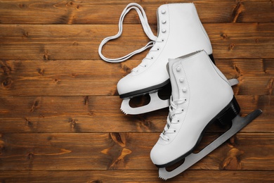 Pair of white ice skates on wooden background, top view. Space for text