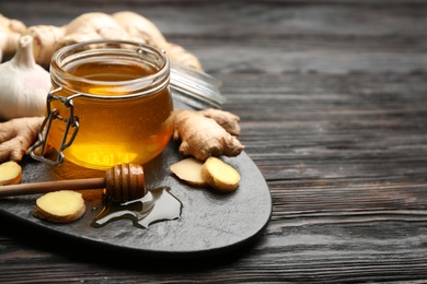 Photo of Ginger and honey on black wooden table, space for text. Natural cold remedies