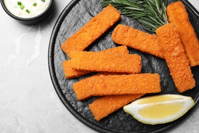 Fresh breaded fish fingers and lemon served on light grey table, flat lay