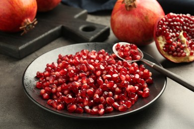 Photo of Ripe juicy pomegranate grains on grey table