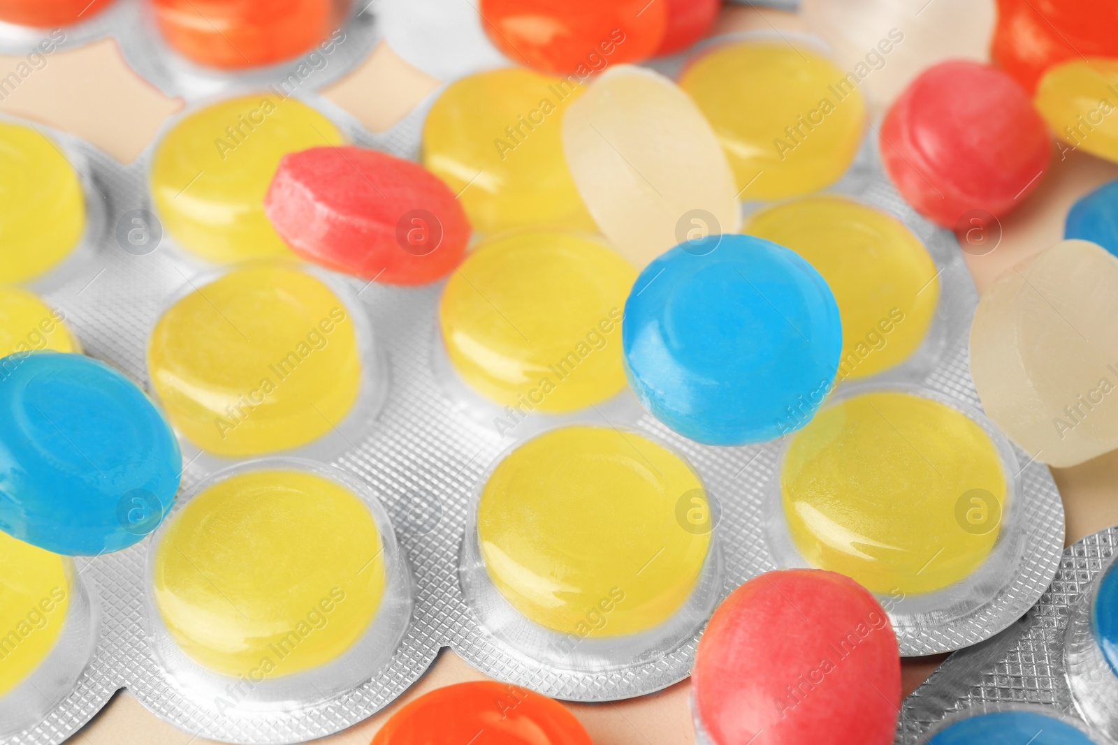 Photo of Blisters and many colorful cough drops as background, closeup