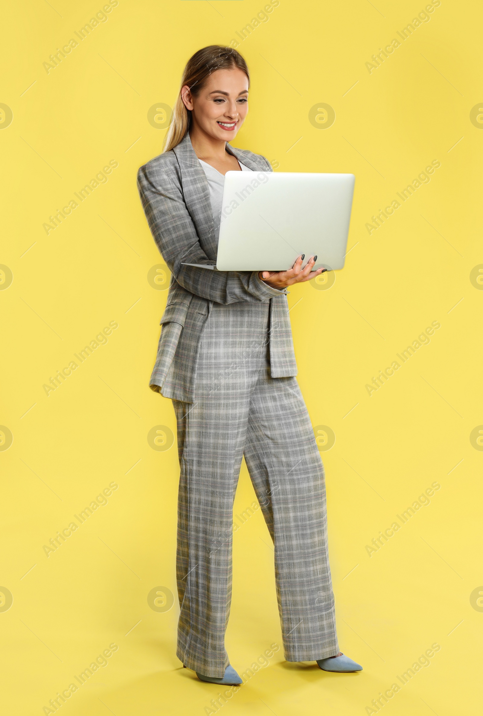 Photo of Beautiful woman using laptop on yellow background