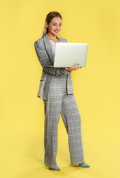 Beautiful woman using laptop on yellow background