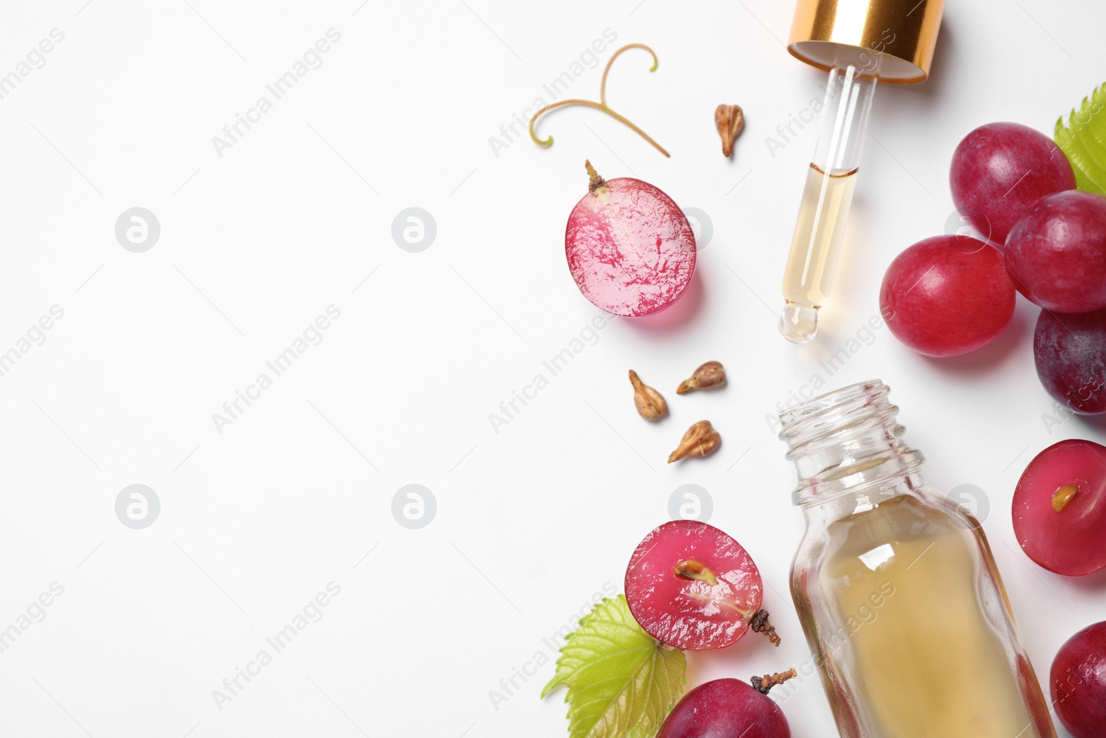 Photo of Composition with bottle of natural grape seed oil on white background, top view. Organic cosmetic