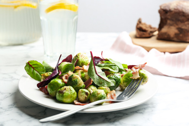 Photo of Delicious Brussels sprouts with bacon on table