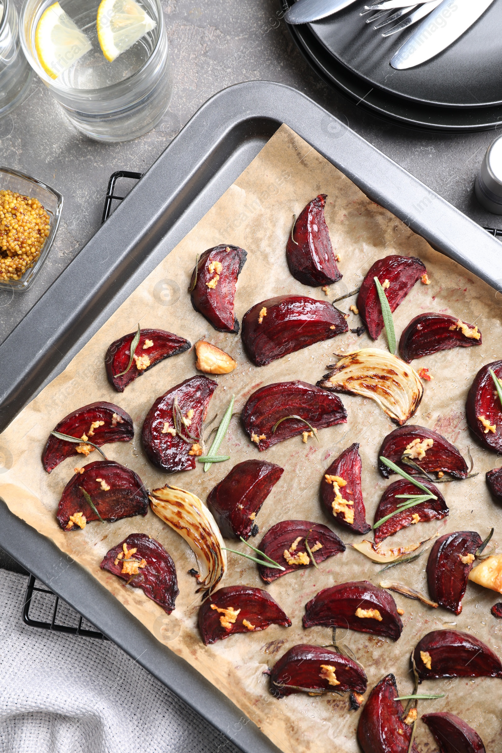 Photo of Baking tray with roasted beetroot slices on grey table, flat lay