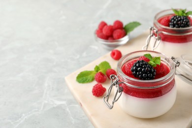 Photo of Delicious panna cotta with fruit coulis and fresh berries on light grey table. Space for text