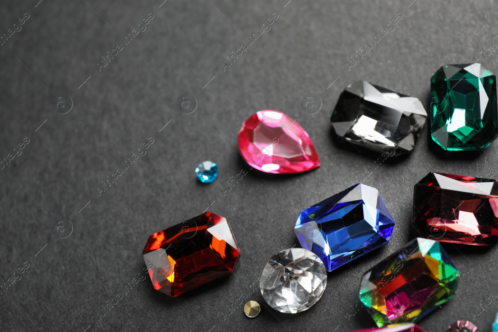 Photo of Different beautiful gemstones on black background, above view