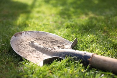 One dirty shovel on green grass outdoors, closeup