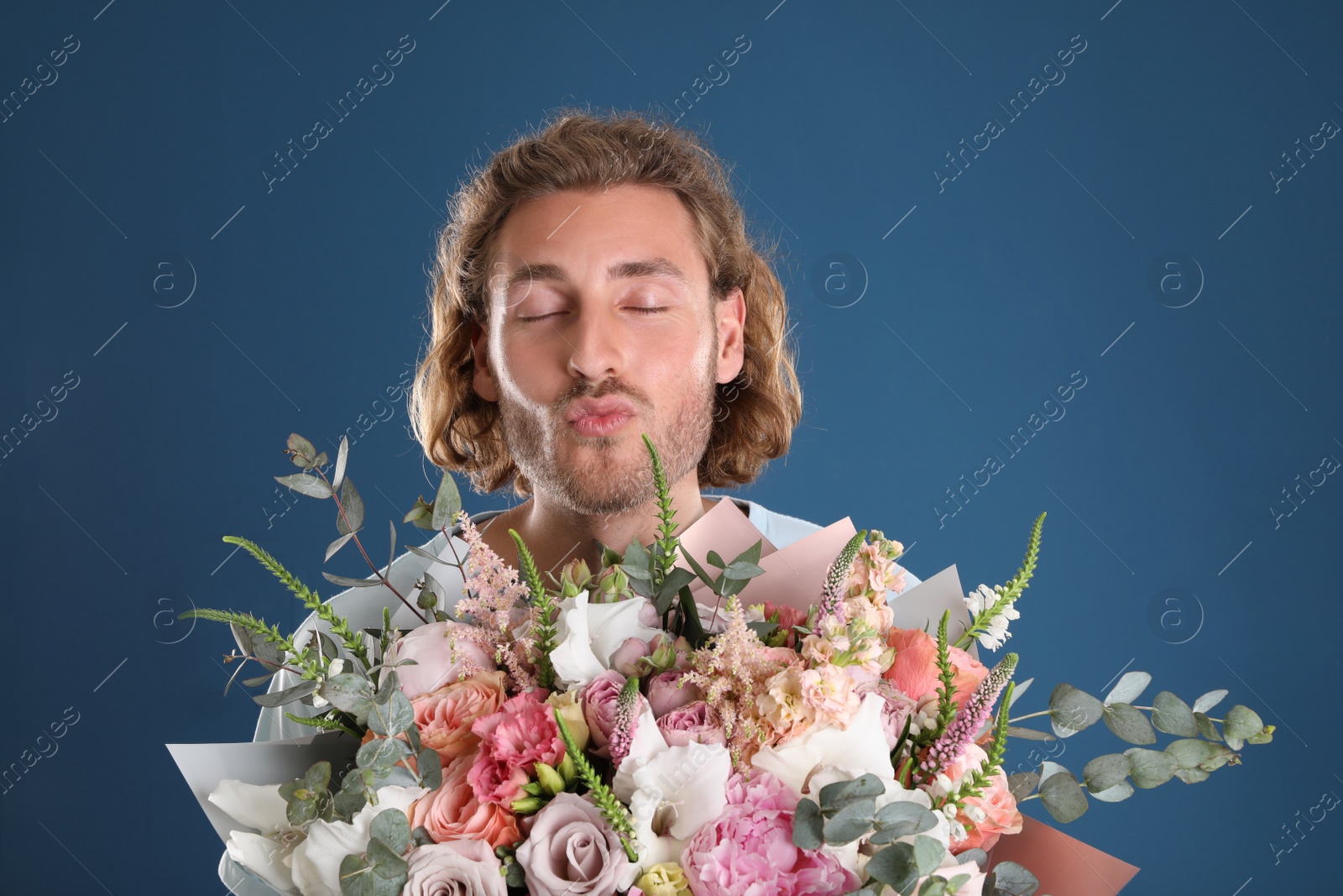 Photo of Young handsome man with beautiful flower bouquet on blue background