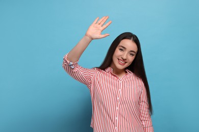 Photo of Happy woman giving high five on light blue background, space for text