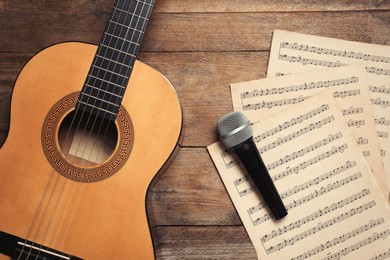 Photo of Composition with guitar and music notations on wooden table, flat lay