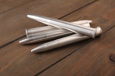 Many metal bullets on wooden table, closeup