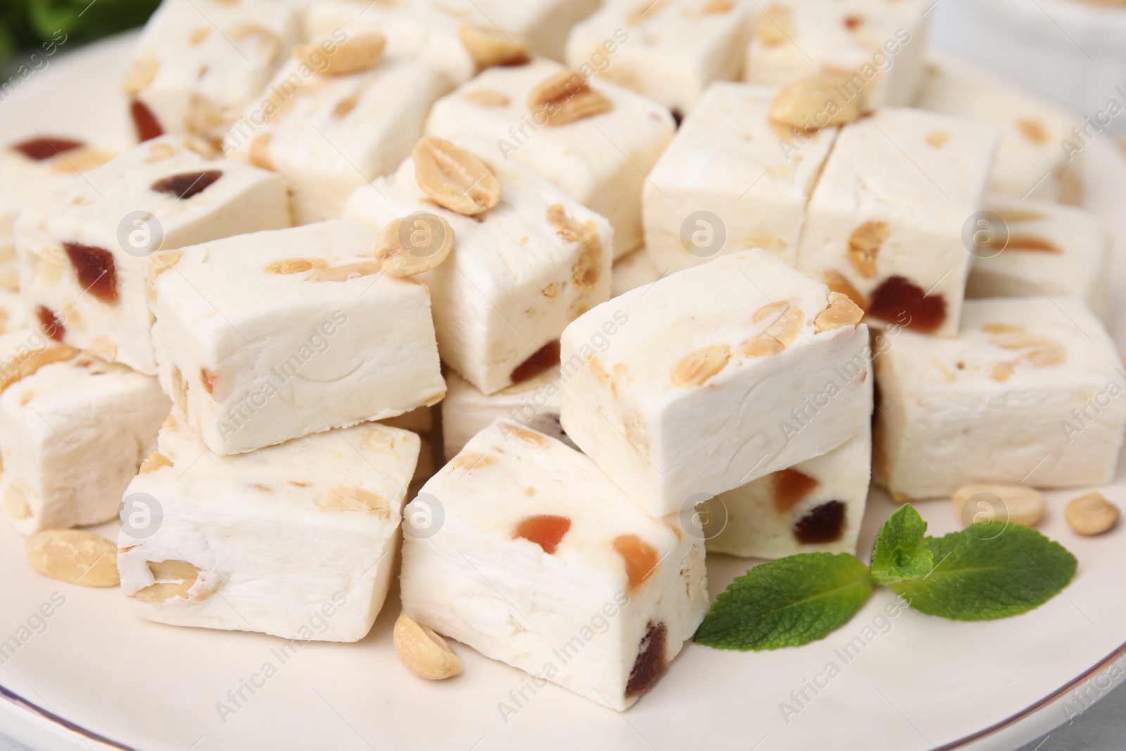 Photo of Pieces of delicious nutty nougat on plate, closeup