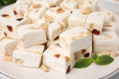 Photo of Pieces of delicious nutty nougat on plate, closeup
