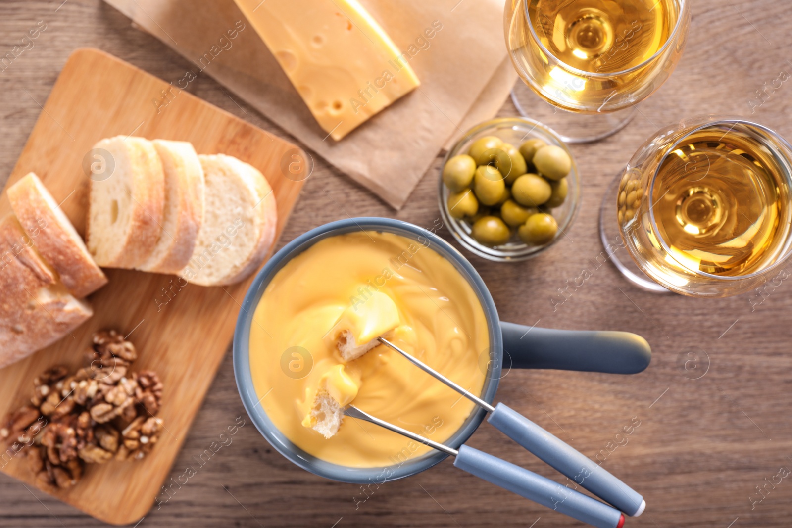 Photo of Flat lay composition with pot of cheese fondue and wine on wooden table