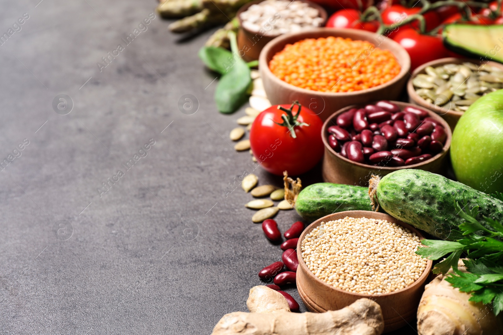 Photo of Fresh vegetables, fruits and seeds on grey table, space for text