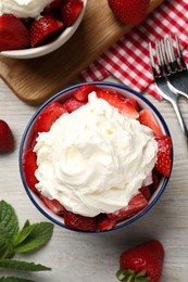 Photo of Delicious strawberries with whipped cream served on wooden table, flat lay