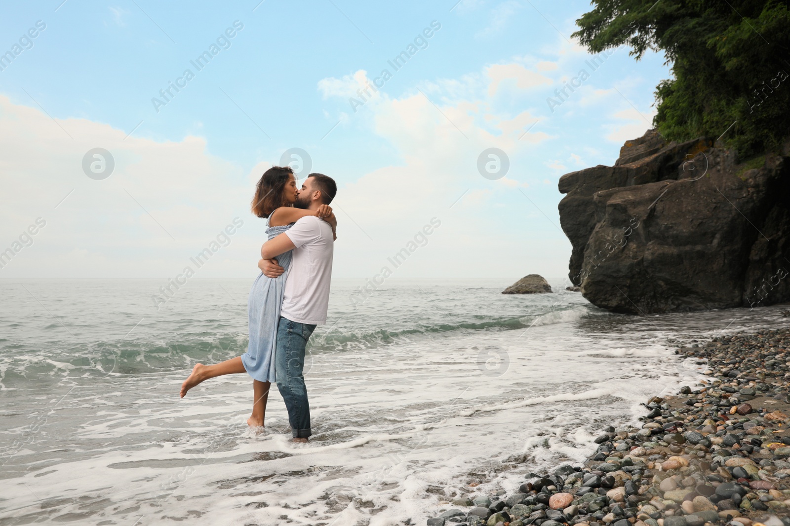 Photo of Young couple kissing on beach near sea, space for text