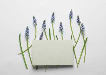 Photo of Beautiful spring muscari flowers and card on light background, flat lay. Space for text