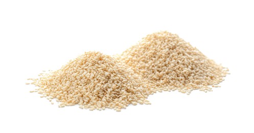 Photo of Piles of sesame seeds on white background