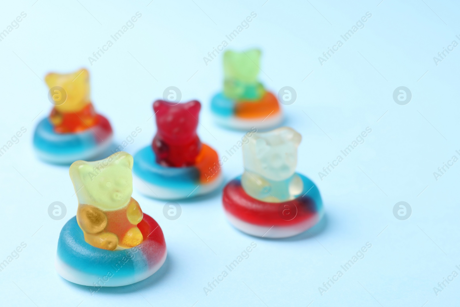 Photo of Jelly bears in rings as water donuts on light blue background
