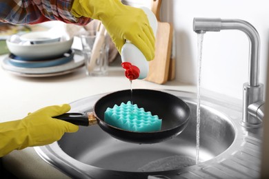 Photo of Woman using cleaning product for washing frying pan in sink indoors, closeup