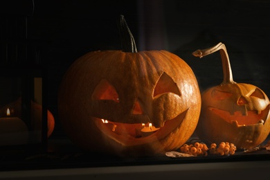 Halloween pumpkin heads. Jack lanterns on windowsill, view through glass