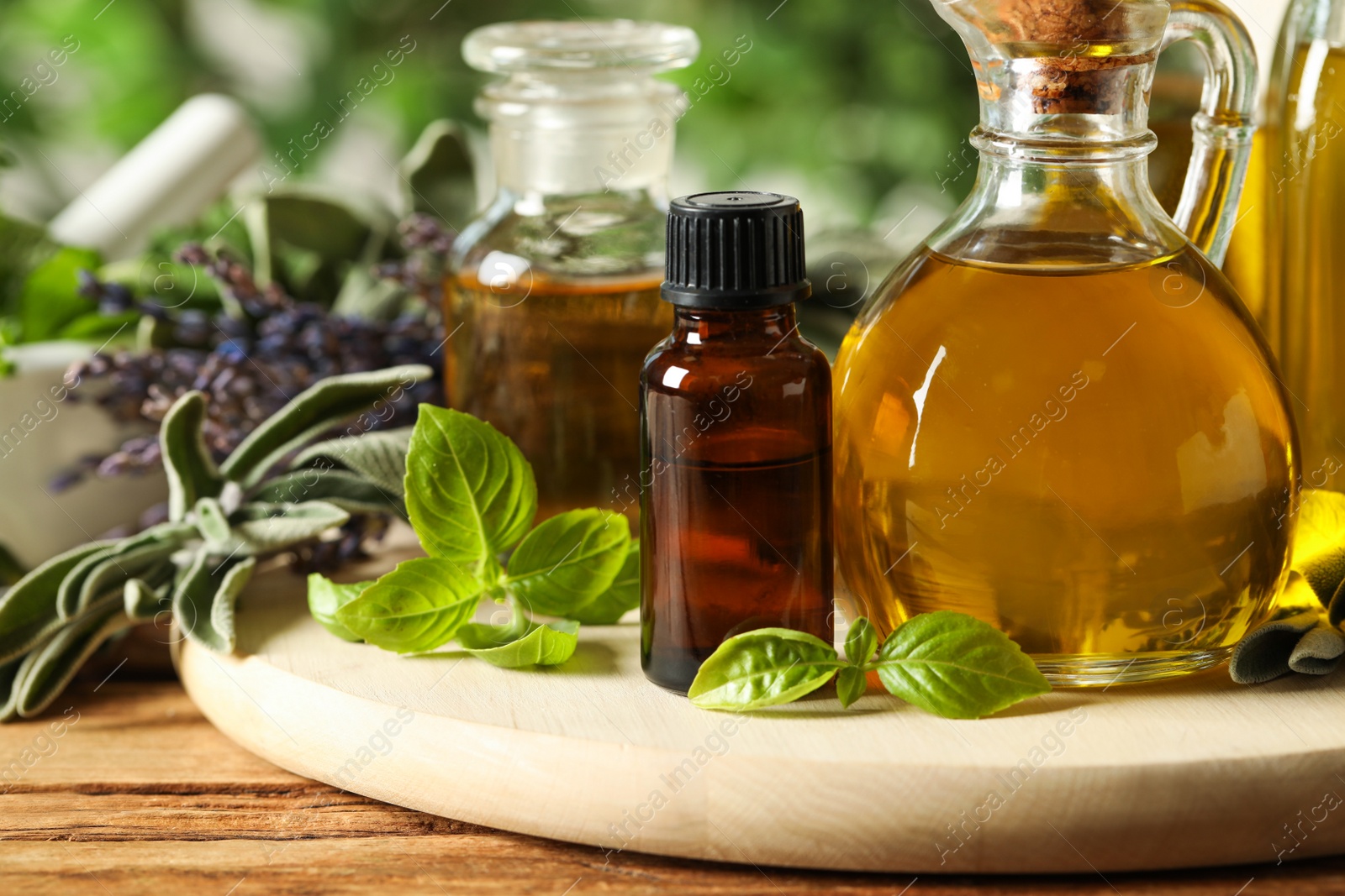 Photo of Different fresh herbs with oils on wooden table, closeup