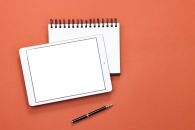 Modern tablet, notepad and pen on color background, flat lay. Space for text