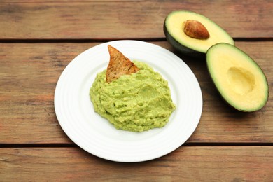 Photo of Delicious guacamole, avocado and nachos on wooden table