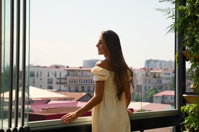 Photo of Beautiful young woman with long hair standing on balcony