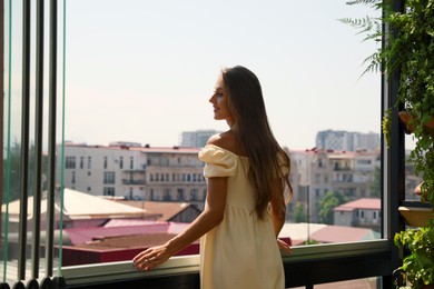 Beautiful young woman with long hair standing on balcony