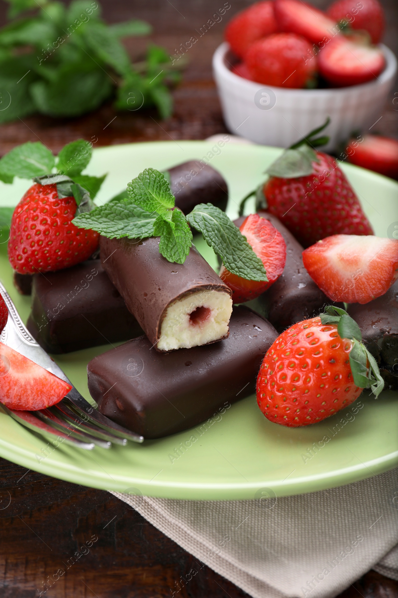 Photo of Delicious glazed curd snacks with fresh strawberries and mint on wooden table