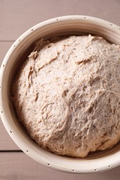 Fresh sourdough in proofing basket on wooden table, top view