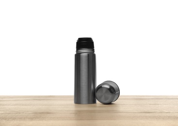 Stylish thermo bottle on wooden table against white background