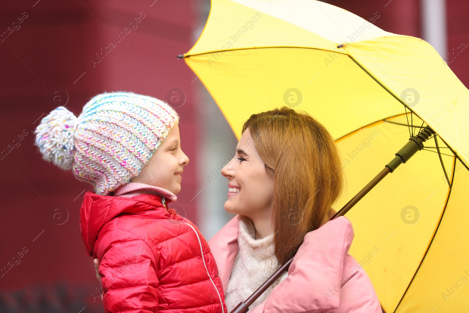 Photo of Mother and daughter with umbrella in city on autumn rainy day