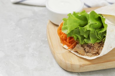 Photo of Delicious tortilla wrap with tuna and sauce on light grey table, closeup. Space for text