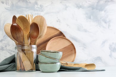 Different dishware and utensils on white marble table against textured wall. Space for text