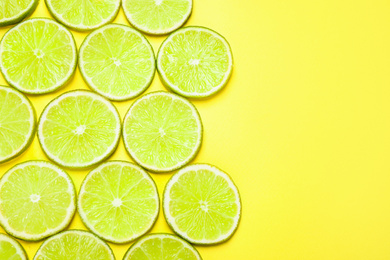 Juicy fresh lime slices on yellow background, flat lay. Space for text