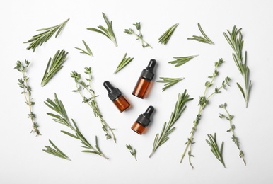 Photo of Bottles of rosemary oil and fresh twigs on white background, top view