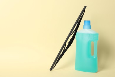 Bottle of windshield washer fluid and wiper on beige background. Space for text