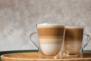 Tray with glass cups of caramel macchiato on table, space for text