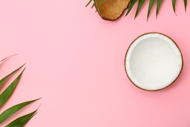 Fresh coconut and palm leaves on pink background, flat lay. Space for text